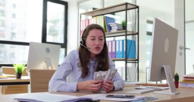 Kadın çağrı merkezi operatörü ofisteki bilgisayar başında oturmuş dolarları sayıyor. İnternet işi uzaktan çalışma ve ağ üzerinden çevrimiçi konferanslar ve video çağrıları