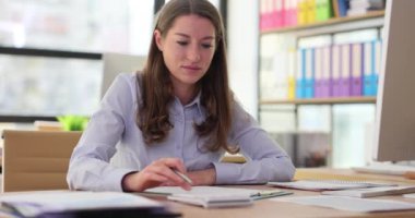 Ofiste hesap makinesiyle çalışan bir iş kadını mali rapor yazıyor. Gelir ve harcamaların mali istatistikleri