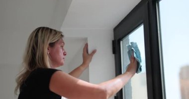 Ev hanımı pencereleri paçavrayla siler. Temizlik servisi