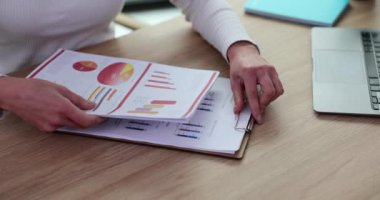 Finansal rapor belgesinin önünde oturan ve grafikleri olan iş kadınlarının yakınlaşması. İş kadını şirket kar sonuçlarını ve borsayı tartışmaya hazır