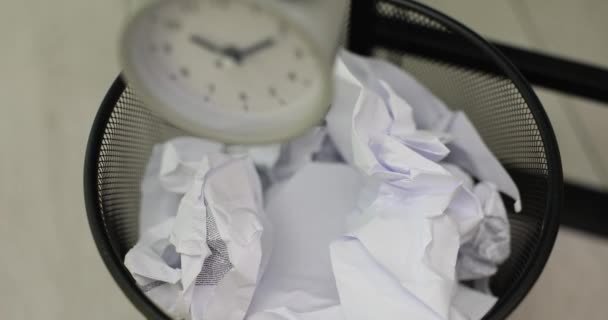 目覚まし時計と女性はそれを粉砕された紙で作ることができるゴミ箱に投げます アジェンダの時間管理と残業 — ストック動画