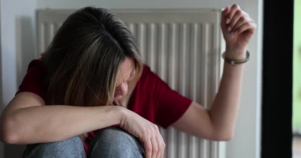 女性の手はラジエーターに手錠をかけられています 女性に対する家庭内暴力 — ストック動画