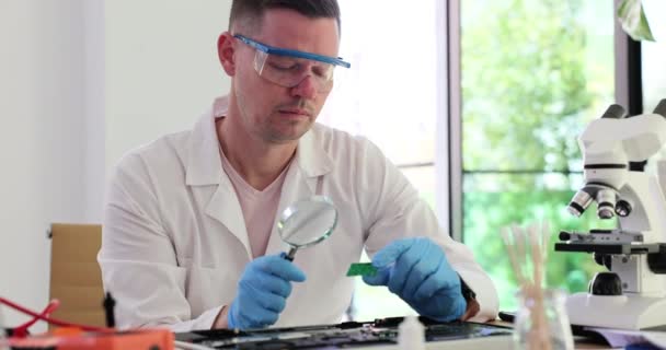 Ingeniero Masculino Pensativo Gafas Utiliza Lupa Para Estudiar Microcircuito Reparación — Vídeos de Stock