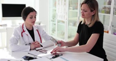 Kadın hasta hastanede doktora para veriyor. Sağlık hizmetlerinde yolsuzluk ve rüşvet
