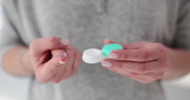 Kadın parmağı plastik konteynırdan lens çıkarıyor. Lensler takıldığında miyop ve hiperopi düzeltilir