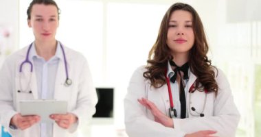 Kollarını kavuşturmuş kadın meslektaşının yanında duran yakışıklı, mutlu erkek doktor. Sağlık hizmetleri ve sigorta
