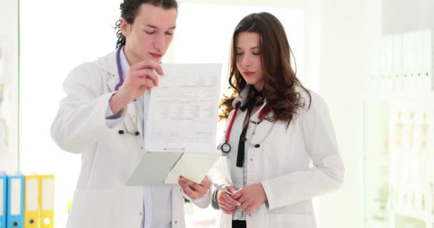 两名医生在讨论治疗建议时 将病历档案保存在剪贴板上 与外科医生的咨询 帮助和经验 — 图库视频影像