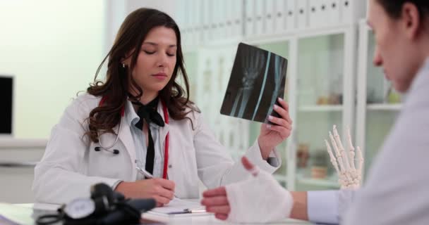 Lekarz Rozmawia Pacjentem Ranną Ręką Pokazuje Prześwietlenie Urazy Dłoni Leczenie — Wideo stockowe