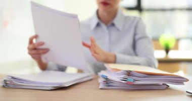 Bayan çalışan, evraklarla dolu dosyaları ofisteki masanın üzerine koyar. Şirketin iş yerinde uzman olarak çalışma zamanı.