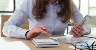 Kadın muhasebeci hesap makinesinde hesap yaparak para sayıyor. Konsantre kadın çalışan, doğruluk için hesap makinesine güvenerek finansal hesaplamalar yapar