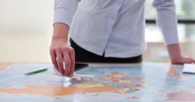 Genç bir kadın muhtemel uçuş rotalarını takip eden bir uçak modeli taşıyor. Bayan harita başında duruyor ve minyatür uçak planlamasına rehberlik ediyor. Sonraki yolculuk macerası yavaş çekim.