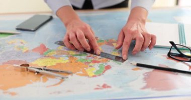 Kadınlar haritadaki ülkeler arasındaki mesafeyi cetvel kullanarak ölçüyorlar. Dişi seyahat acentesi, cetveli dikkatlice haritaya yerleştirir.