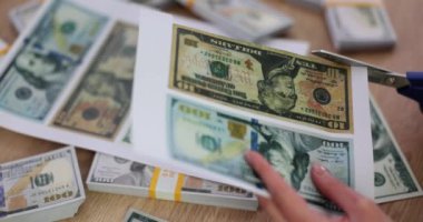Yetenekli bir insan, dolarların kenarlarını hassasiyetle keser. İşinin ehli bir çalışan, istenmeyen materyalleri ortadan kaldırmak için makas kullanarak kağıda basılmış sahte banknotları keser.