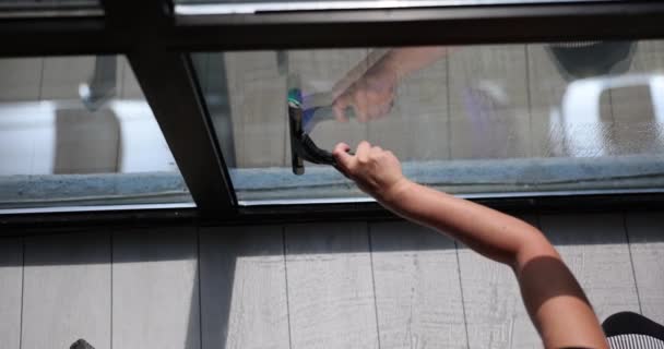 女性は家の清潔さを維持するプロセスを楽しみます 女性は徹底的なクリーニングを保障するストリークなしの終わりを達成するために窓のクリーナーを使用します — ストック動画
