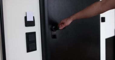 İnsan boş koridorun modern kapısını yavaş çekime açar. Adam dairesinin kapısını açmak üzere. Modern güvenlik-uyumlu kapının gösterimi