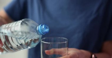 Kadın şeffaf cam ağır çekimde temiz su döker. Susamış kadın şişeden bardağa saf su doldurur. İçmeye gider.
