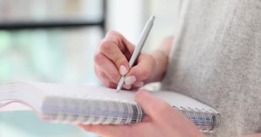 Kadın, kağıt defterin sayfasını kişisel düşünce ve anılarla dolduruyor. İş kadını kişisel planlama günü çizelgesinde yazıyor
