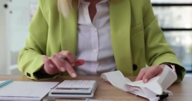 Kadın muhasebeci, ofisteki ahşap masada oturan hesap makinesinin faturalarını kontrol ederek şirket giderlerini hesaplar. Finans uzmanının evrak işleri ve iş akışı