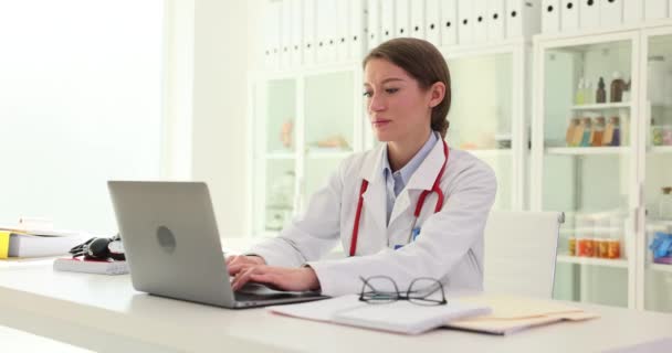 매력적인 의사는 진료소에서 일하고 노트북을 사용하고 서류를 완료합니다 의사는 의학을위한 — 비디오