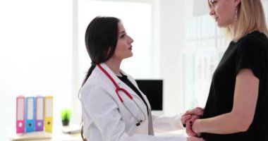 Doktor konuşuyor ve klinikte üzgün kadın hastalara bakıyor. Sağlık hizmetlerinde tıbbi destek