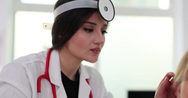 Dişi otolarogengolog otoskop kullanarak kulağı inceliyor. Yetişkinler için işitme testi