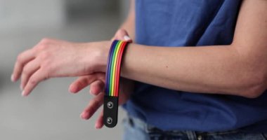 Yakından bakınca LGBT bayrağı renginde bir bilezik takıyor. lgbt sembollü kadın eli
