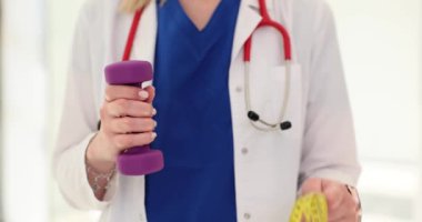 Doktorun elinde bant ve dambıl var. Spor sağlık ve spor
