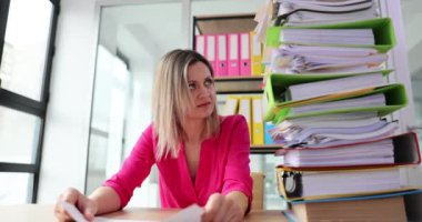 Vergi yükü ve kağıt dosyaları olan ve yardım isteyen üzgün bir kadın. İş yerinde zorluklar ve yorgunluk
