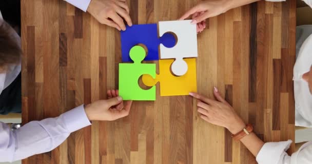 ミーティングテーブルに色のついたパズルをまとめた2人のビジネス同僚のトップビュー 成功したチームと会社を構築するためのコンセプト — ストック動画