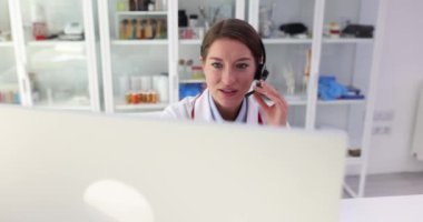 Kulaklıklı güzel kadın pratisyen klinikte bilgisayarla video konferans yoluyla konuşuyor. Video görüşmeleri aracılığıyla çevrimiçi istişareler terapisti