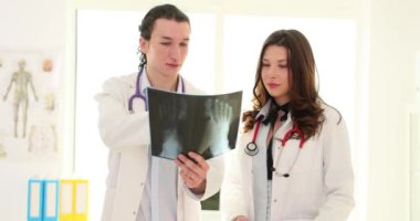 Kadın cerrah, klinikteki erkek travmatoloğa röntgen sonuçlarını gösteriyor. Tıp arkadaşları hastane ve tıp konseptinde ayak kemikleri konuşmalarının radyografisini tartışıyor