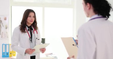 İki doktor tıp bürosunda buluşup el sıkışıyor. Beyaz önlüklü iki tıp çalışanı hastanede toplantı yapıyor.