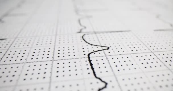 EcgまたはEkgグラフのプリントアウトは 患者の心拍数と電気活動を示しています 大人の電気カルディオグラムおよび医学検査の線形表示 — ストック動画