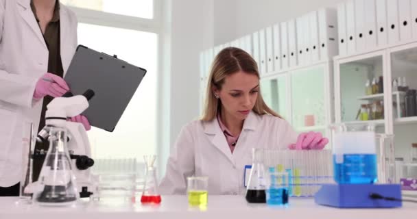 Vrouwelijke Onderzoeker Zit Aan Tafel Laboratorium Met Microscoop Gekleurde Vloeistoffen — Stockvideo