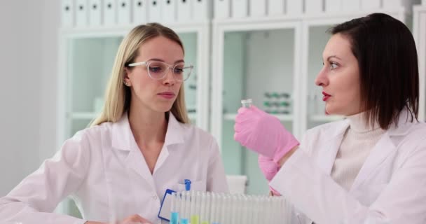 化粧品科学者と同僚は ガラスフラスコから赤い液体物質を嗅ぎ 実験室で実験を行った 実験室および不快な臭いの化粧品のテスト — ストック動画