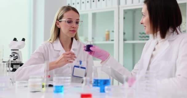 化妆品化学家 科学家和同事从玻璃瓶中嗅出蓝色紫罗兰液体物质 并在实验室进行实验 在实验室测试化妆品 — 图库视频影像