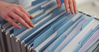 Bayan ofis çalışanı şirket arşivi için dosyaları kutudan çıkartıyor. Şirket işlerinde verilerle çalışmak yavaş çekimde gerçekleşir