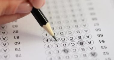 Öğrenci sınav sorularına kurşun kalemle cevap veriyor. Dişi gölgeler çemberi cevapları kalemle işaretliyor. Anket tamamlama konsepti yavaş çekim