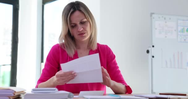 女性労働者は手紙を開き 悪いニュースを見つけ出し 文書を捨てる オフィスのデスクの女性からの否定的な感情 — ストック動画