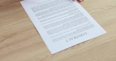 Kadın şirket ofisindeki ahşap masada kontratı reddediyor. Sözleşme imzalamak üzere olan kalem tutan kadının elleri. Kadın anlaşma imzalama konusunda fikrini değiştirdi