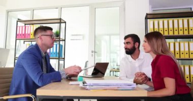 Profesyonel ofis çalışanı gelen belgeleri onaylıyor ve damgalıyor. Genç çift birlikte sevinç anlarını paylaşıyor ve sözleşme onayını kutluyor.