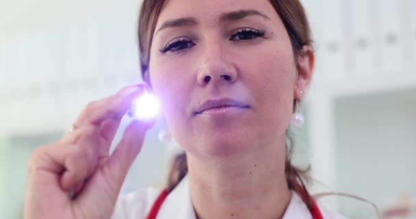 累了的诊所工作人员 负责任的脸在病人寻求帮助时闪烁着微弱的手电筒 检查有关人士的健康状况 — 图库视频影像