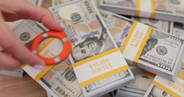 Kadın, dekoratif küçük cankurtaran şamandırasını yığınla doların üzerine yerleştiriyor. Banka çalışanı toplantıda kriz önleyici tedbirlerin sunumu için elverişli bir hatıra kullanıyor