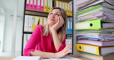 Kadın, gelecekteki istirahat planlarını düşleyen dosyalarla dolu bir masada oturuyor. Sarışın muhasebeci ara verdi. Ofiste çalışan parmakları inceliyor.