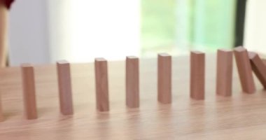 Kadın, ahşap dekoratif bloklardan düşmeyi ve durumu el yordamıyla anlatmayı bıraktı. Ofis tahtasındaki dikdörtgen bloklar. Domino etkisi.