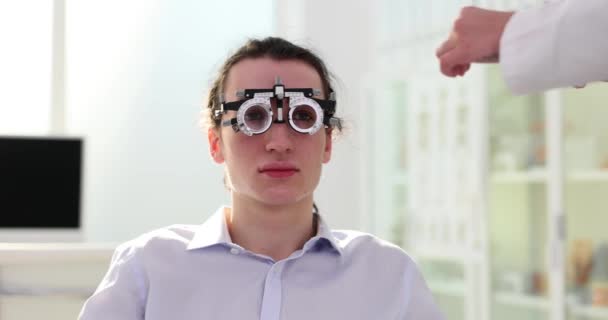 女眼科医生把镜片放在奇观镜框中检查男性患者的视力 眼科医生检查眼疾办公室的男病人 — 图库视频影像