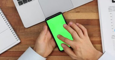 Adam iş yerinde krom ekranlı cep telefonu kullanıyor. Çalışan ofiste internet üzerinden bilgi istiyor. Akıllı telefon aracılığıyla internet iletişimi