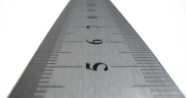 Metal cetvel, beyaz arka planda ölçekli ve basamaklı. Stüdyoda şerit boyunca hareket. Okul malzemeleri ve inşaat aletleri.