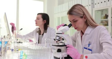Sarışın kimyager, deneyleri ağır çekimde yapmak için mikroskopla inceledi. Esmer komşu bilgisayarda çalışıyor. Tıp merkezindeki kadınlar.