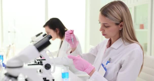 在实验室里 以女性科学家为研究对象 用琵琶蓝色液体滴在培养皿中 检测样品和进行实验慢动作 — 图库视频影像